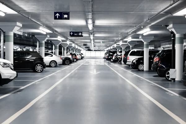 Çizgili park yerleri, yönlendirme tabelaları ve aydınlatmalarıyla düzenli kapalı otopark katı.